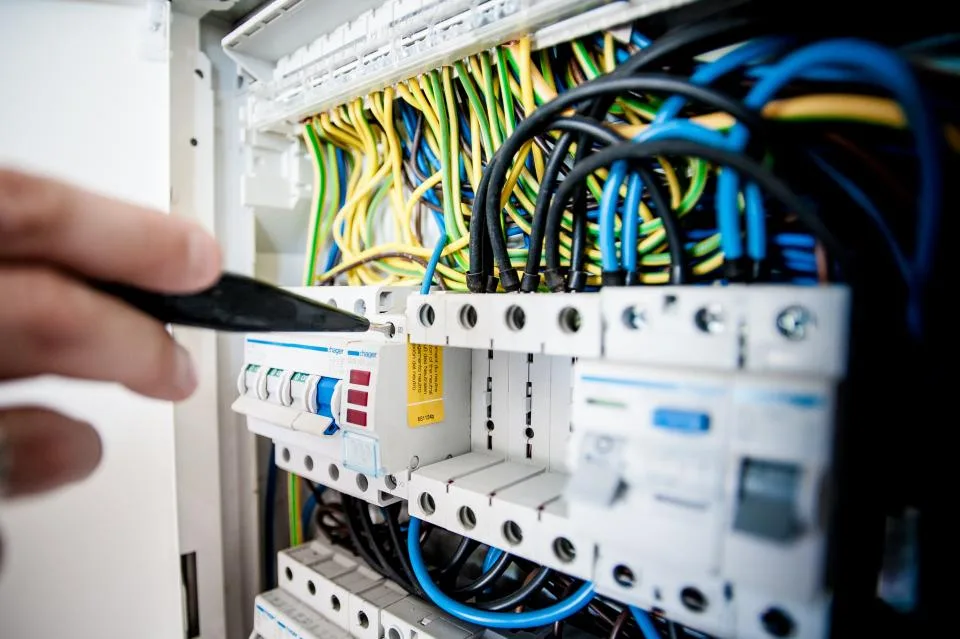Électricien testant un disjoncteur différentiel dans un tableau à Plaisir